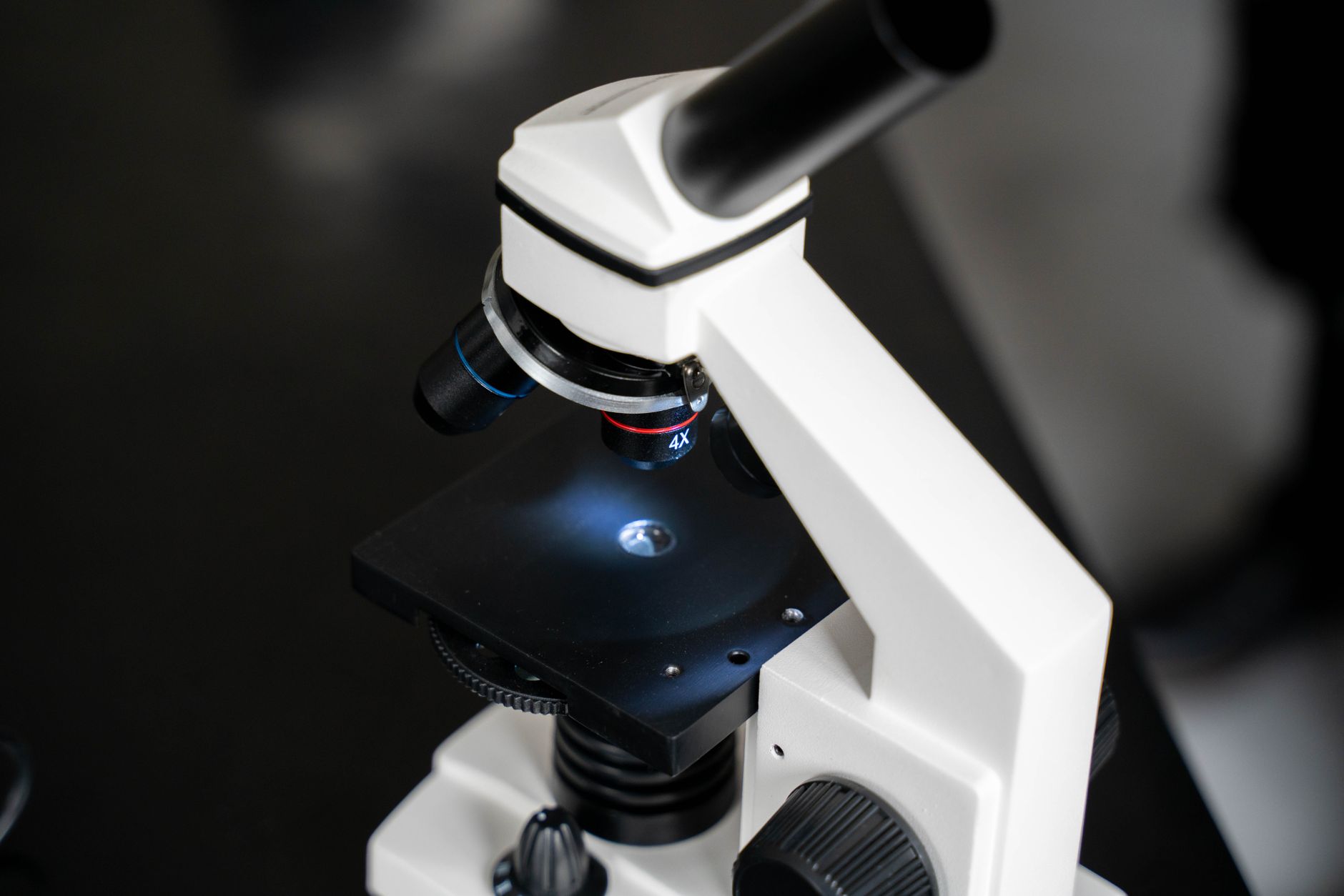 Laboratory microscope with illuminated lens and precision adjustment knobs on a bench